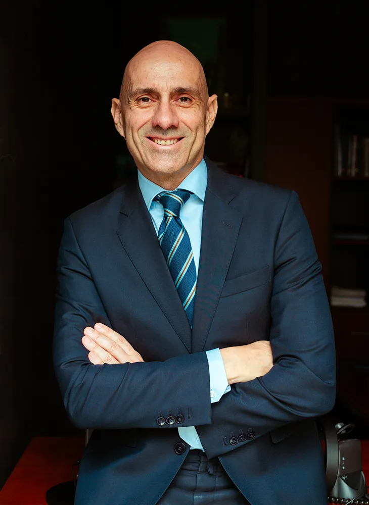 Eduardo Lázaro Despacho Tributario Hombre de negocios sonriente con traje y corbata, de brazos cruzados, en una oficina.